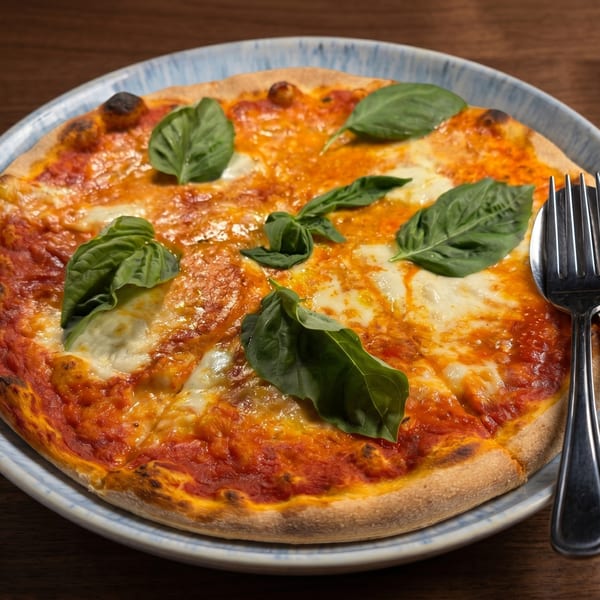 A freshly baked Margherita pizza with melted mozzarella, red sauce, and basil leaves on a plate.